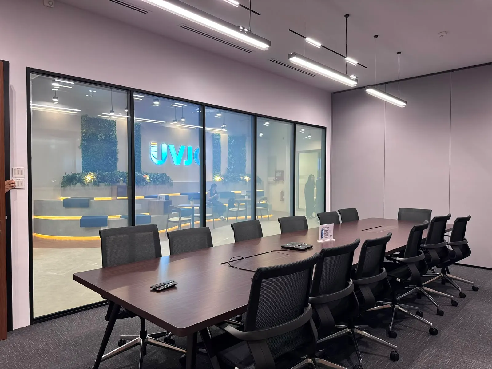 The same boardroom glass with Smart Film switched clear, the lit reception beyond visible through it