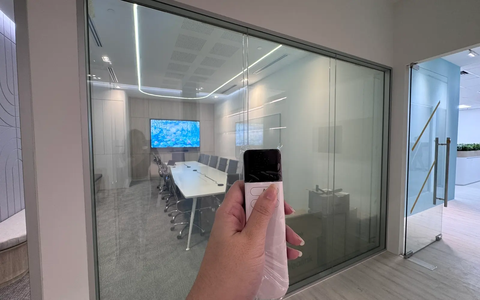 The same Smart Glass partition switched clear, with the boardroom table and screen visible through the glass