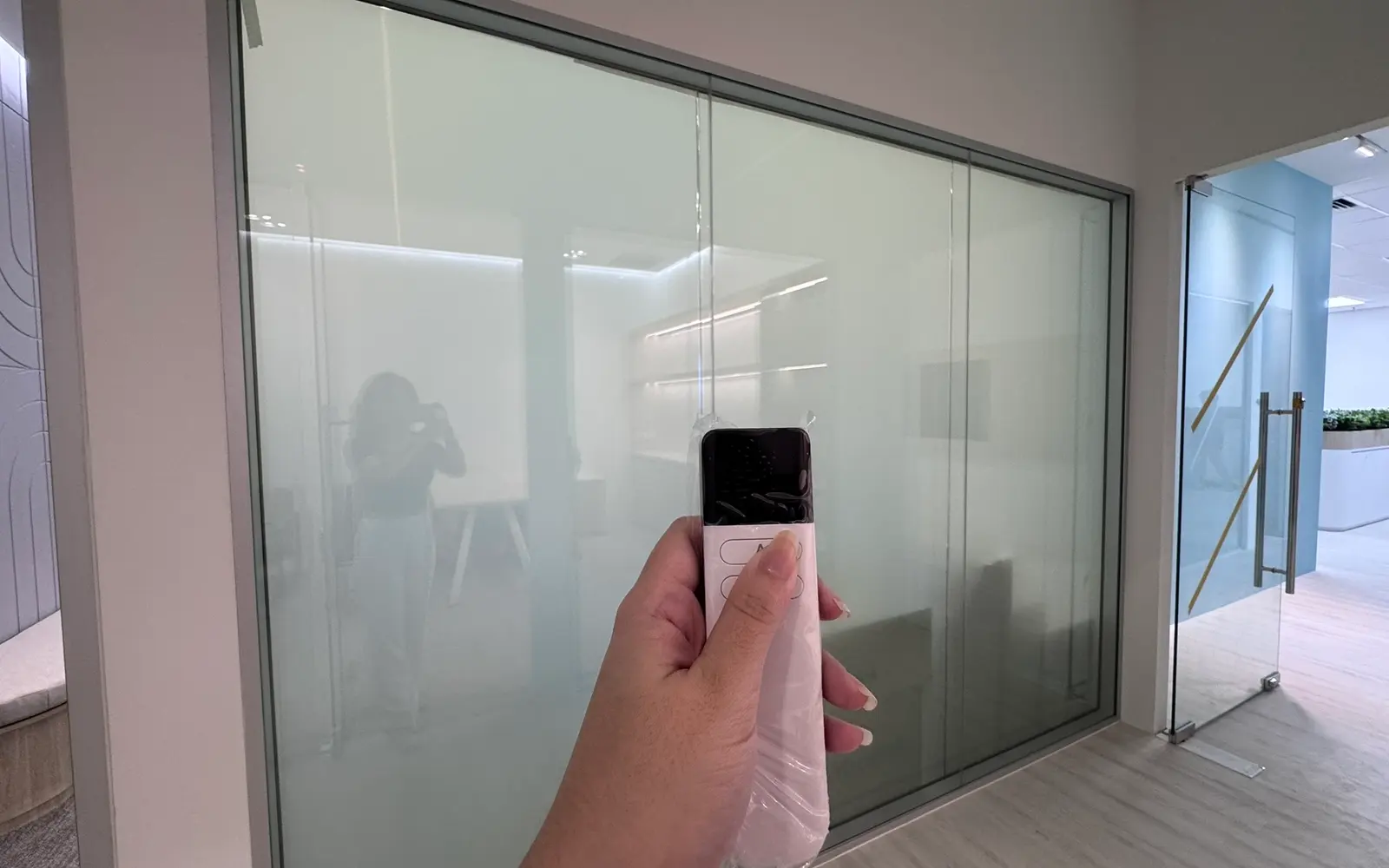 Smart Glass meeting room partition in a Singapore office, frosted for privacy, with the remote control in shot