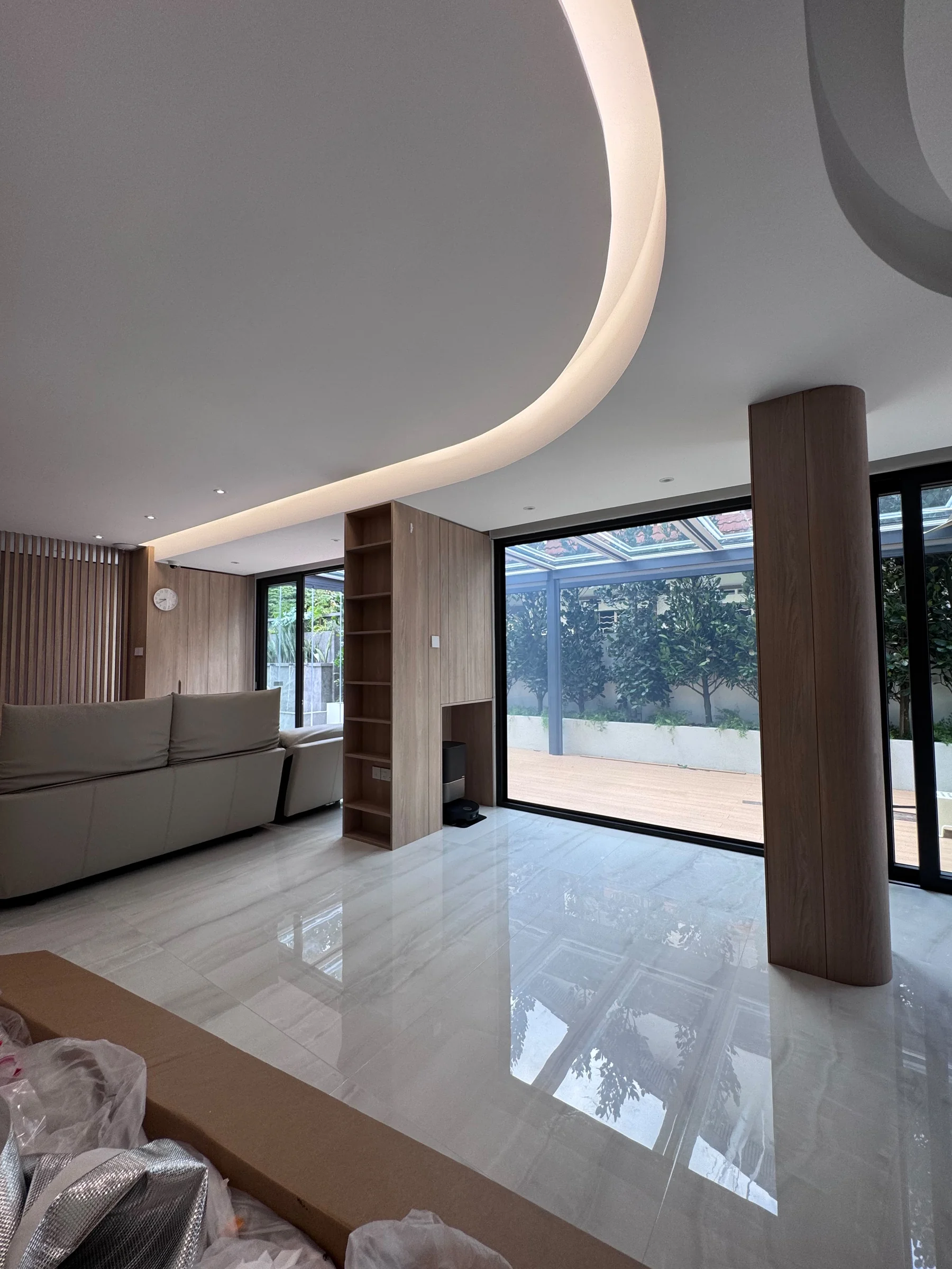 Smart film for homes in clear mode on a living room glass wall in Singapore, open to a landscaped courtyard