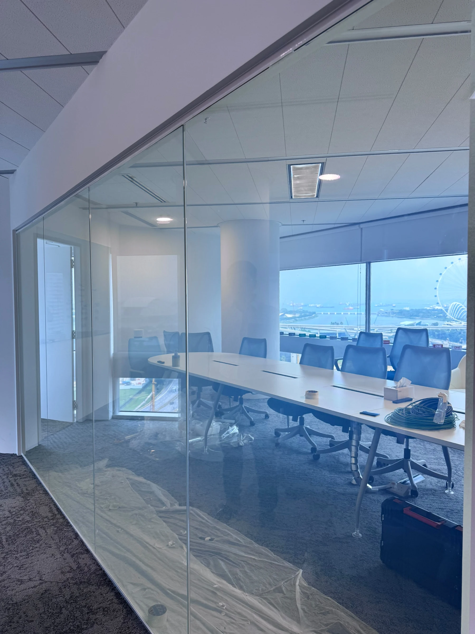 Smart film for office privacy in clear mode on a Singapore meeting room glass partition, boardroom and skyline visible