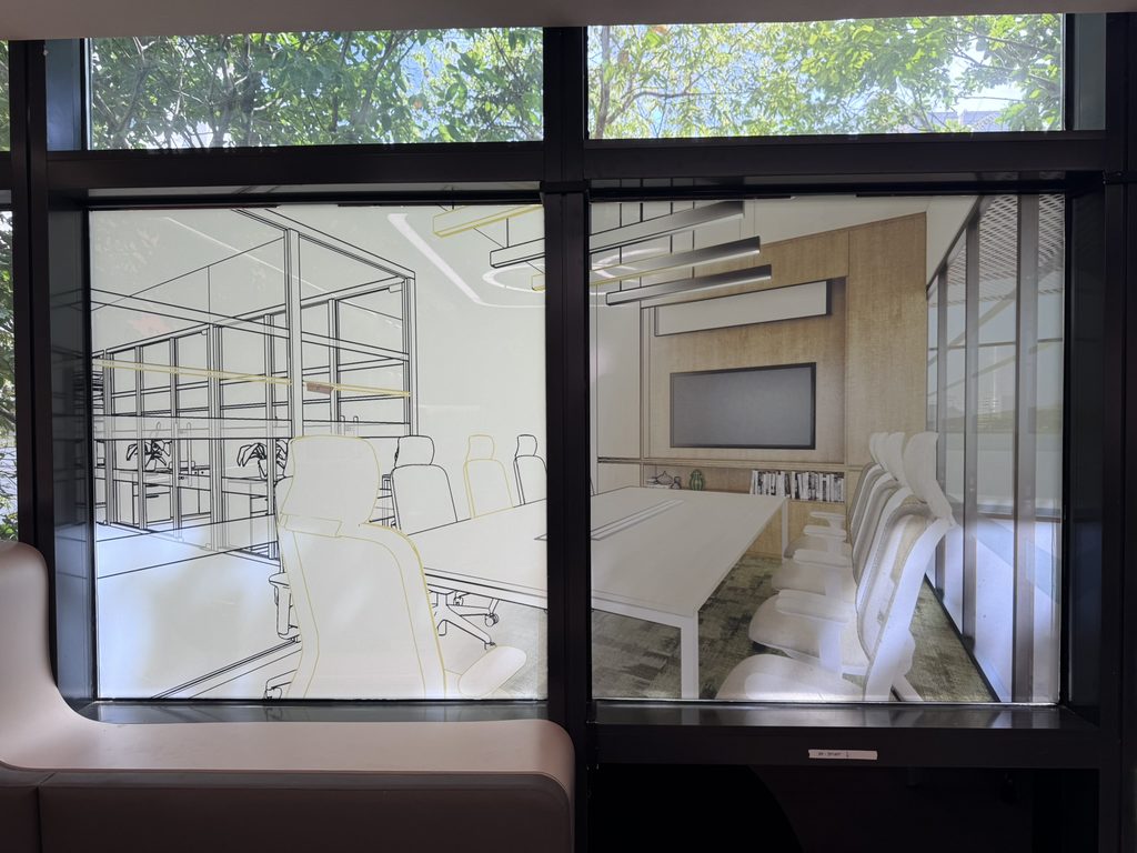 Decorative frosted film graphic on an office glass partition, with the meeting room visible through the clear glass