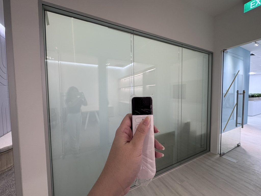 Smart film on an existing office glass partition switched to frosted privacy mode using a handheld remote