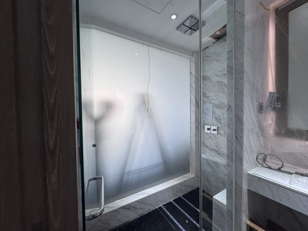 Switchable privacy glass in a bathroom, frosted to screen the shower area while still letting daylight through